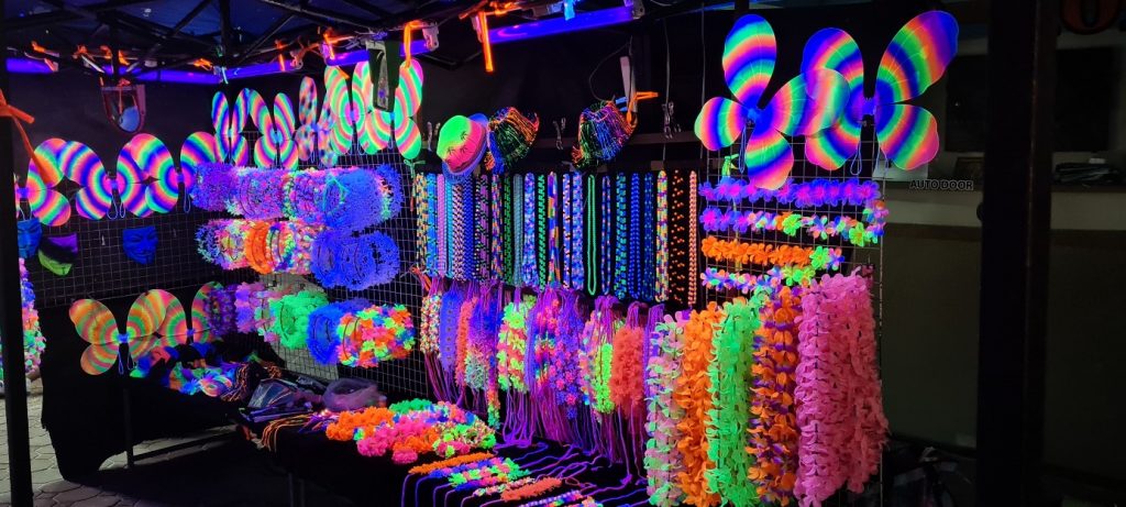 Partyartikel-Verkaufsstand mit nächtlicher Beleuchtung mit fluoreszierenden Bändern und Blumenketten